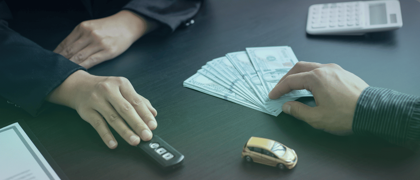 two people at a desk exchanging money and car keys.