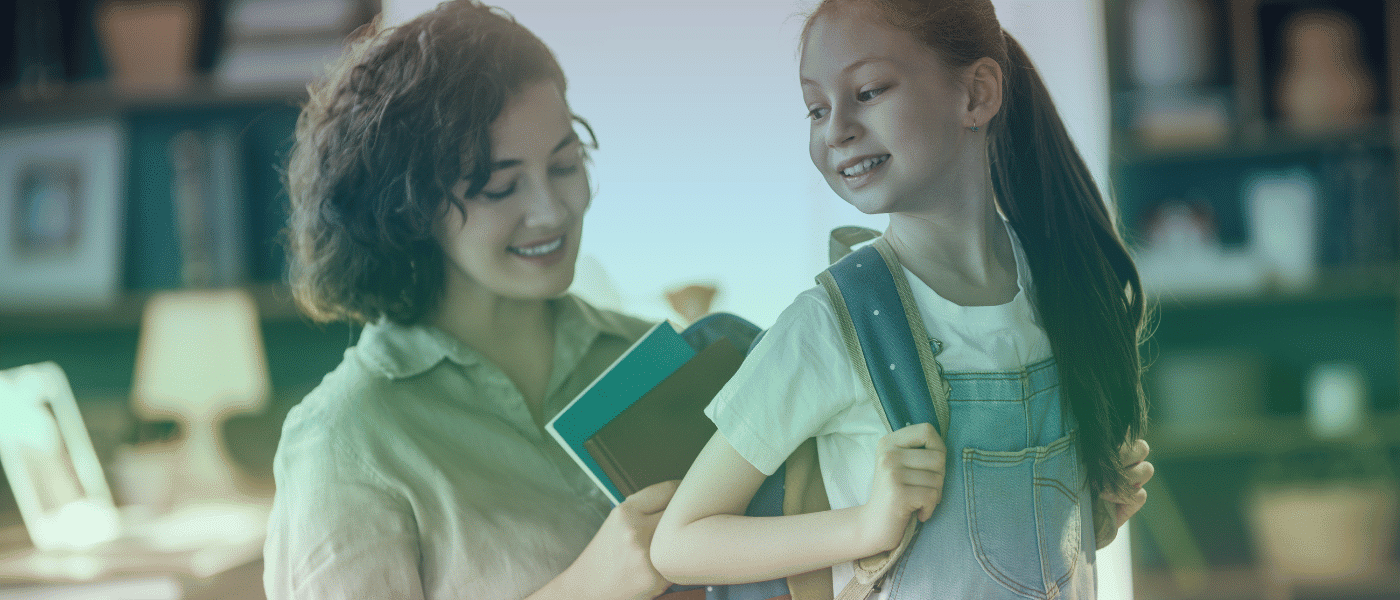 adult woman putting notebooks into child's backpack.
